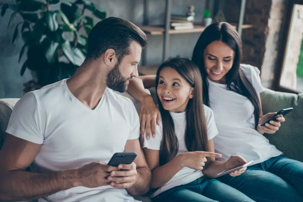 mom and dad hanging out with their daughter while on their phones