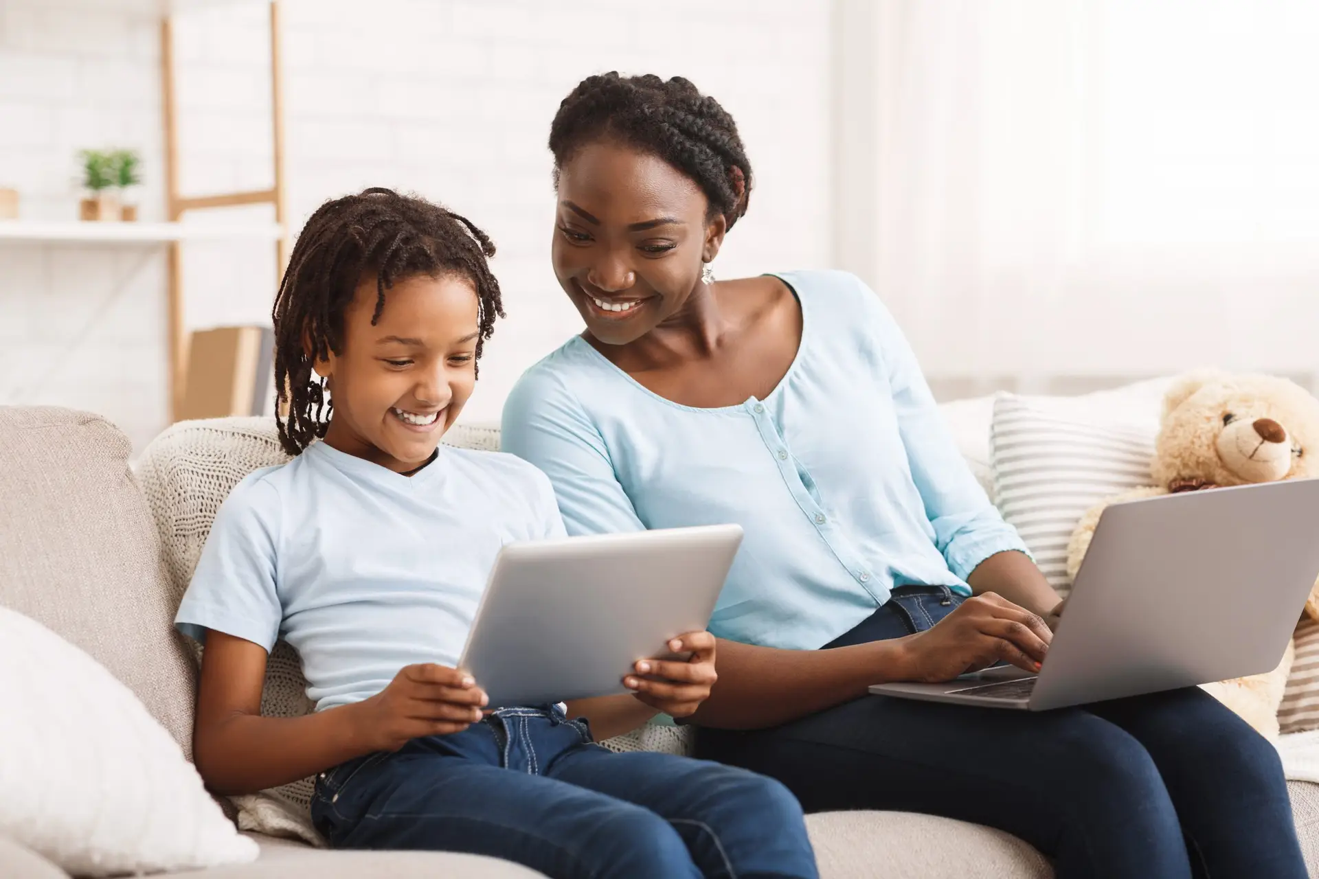 Technology Concept. Happy family sitting on sofa, using laptop and digital tablet at home, free space