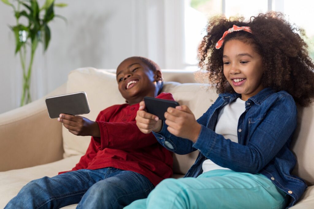 girl and boy playing games on their phones on the couch