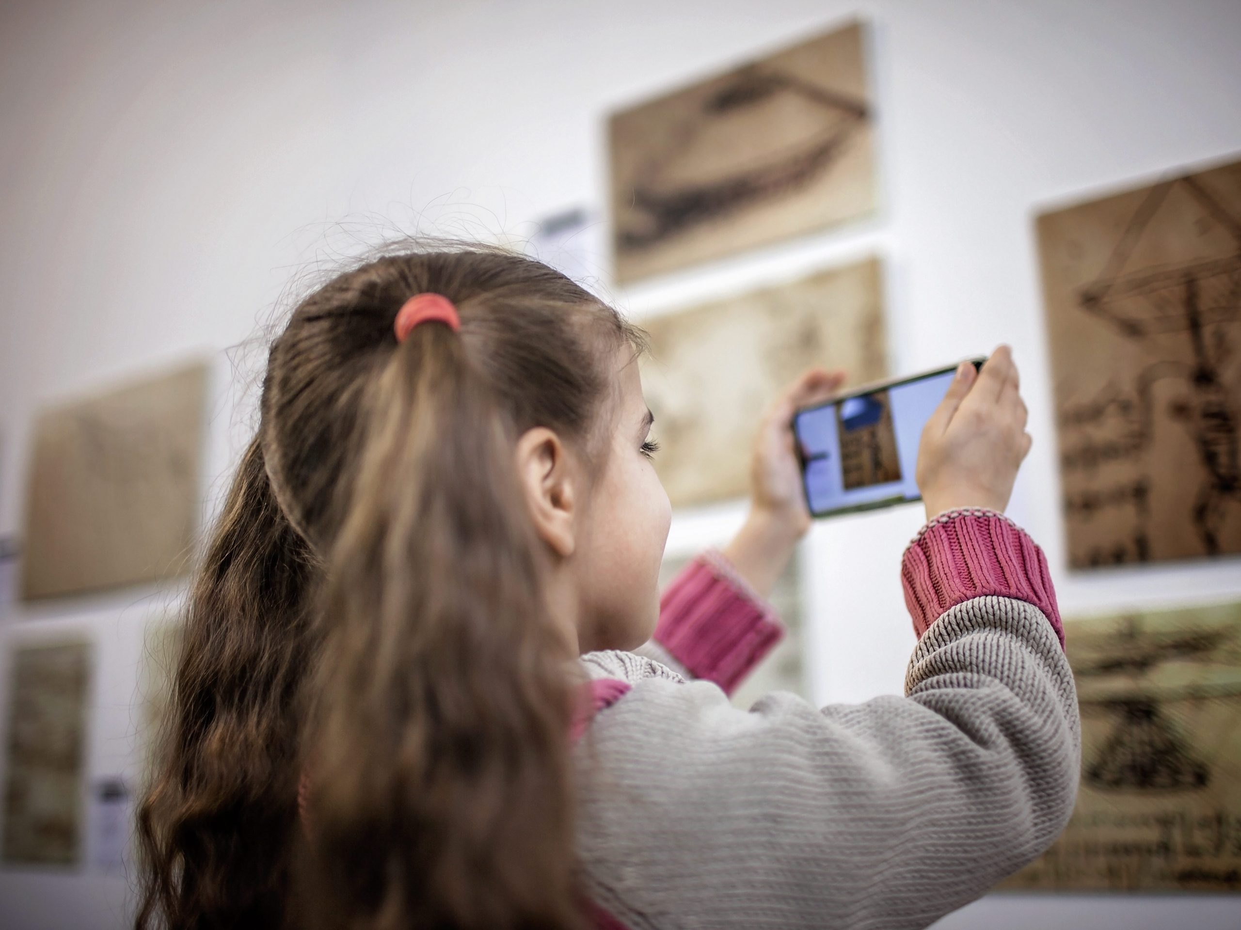 girl using phone in a healthy way to take a photo at a museum