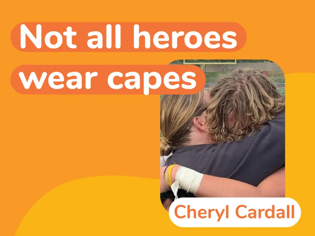 A heartfelt hug between two people with the text "Not all heroes wear capes" and "Cheryl Cardall" on an orange background, highlighting the crucial role of suicide prevention.