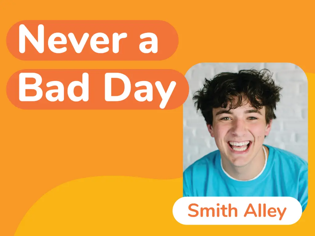 A smiling person with curly hair, donning a blue shirt, stands against a white brick backdrop. The vibrant text, "Never a Bad Day and Smith Alley," overlays an orange and yellow background, bringing to mind the importance of sport safety for kids and what parents need to know.