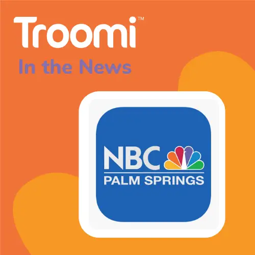 Troomi In the News graphic features a blue NBC Palm Springs logo at its center, set against a vibrant orange background. Troomi: The Perfect Gift for Kids makes it an ideal spotlight for this eye-catching design.