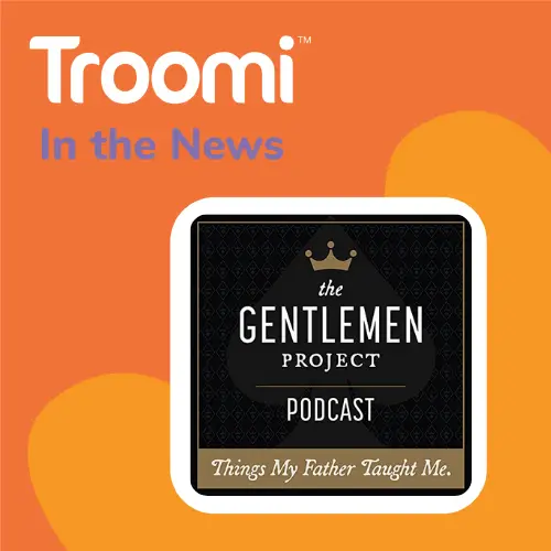 Graphic featuring the Troomi logo and the text In the News. Below is The Gentleman Project Podcast logo with the tagline Gradually Introducing Kids to Tech on a black background with a crown icon. Orange heart shapes decorate the backdrop.