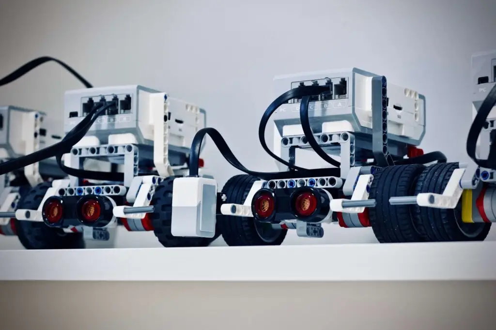 Close-up of two LEGO Mindstorms robots on a white surface, perfect for introducing robotics for kids. The robots feature white bricks, black wheels, and multiple cables, showcasing their programmable components.