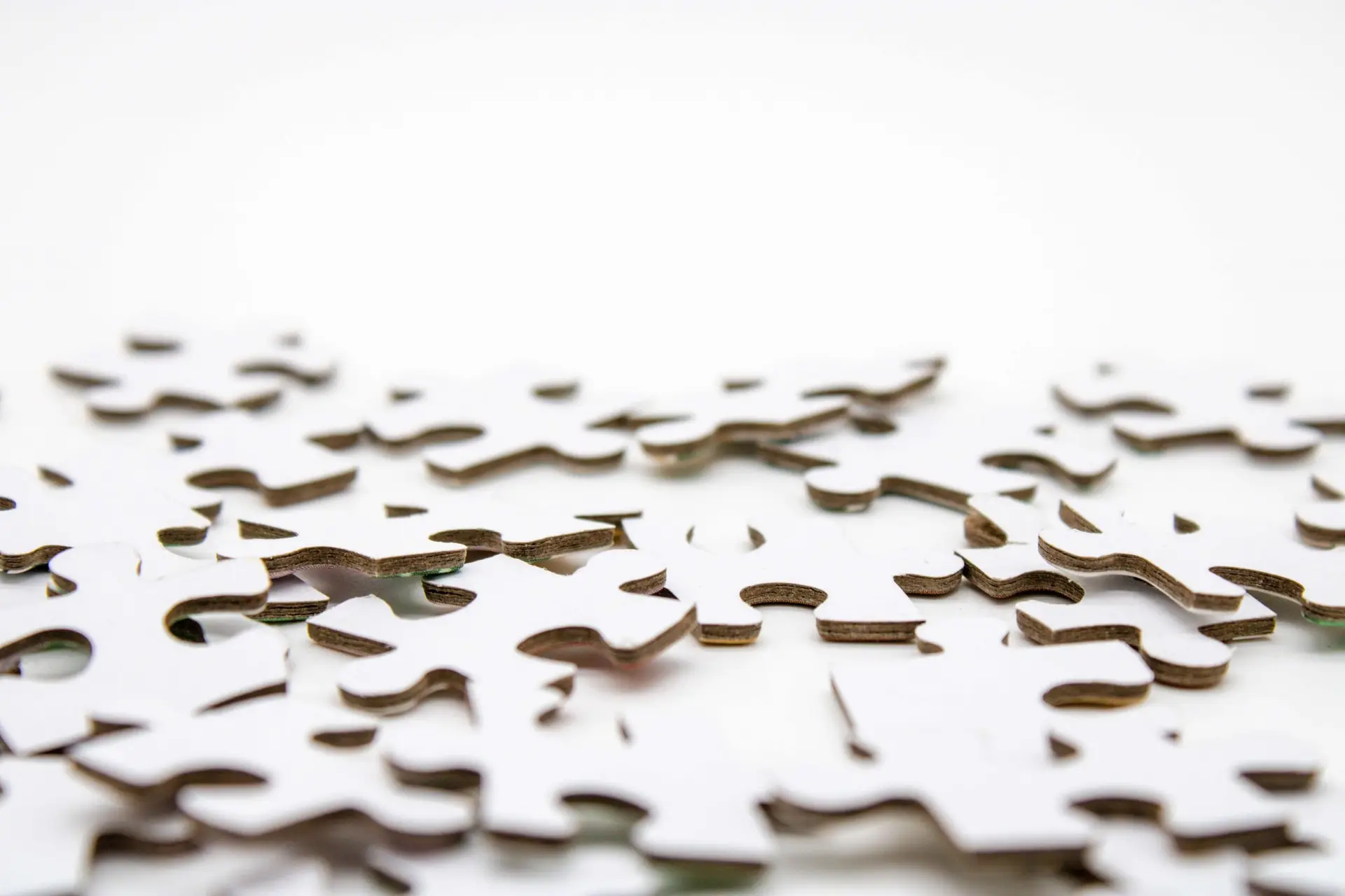 A close-up shot of scattered white puzzle pieces on a white background, reminiscent of puzzles for kids, invites the joy and challenge of piecing together a world in miniature.