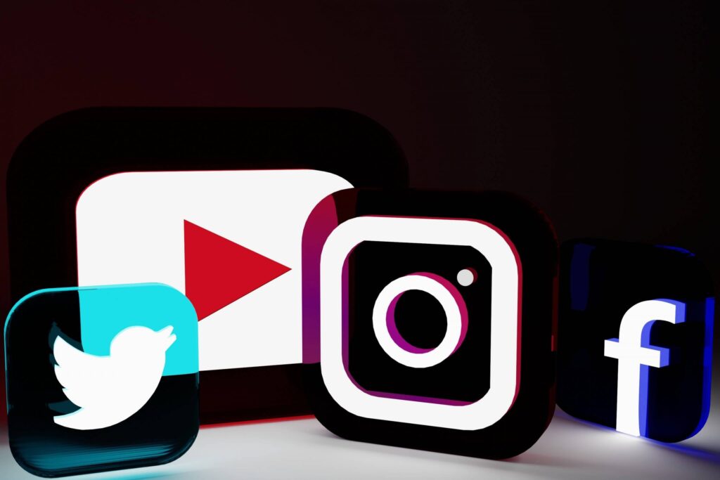 Against a dark backdrop, a captivating display features illuminated social media logos: Twitter's blue bird, YouTube's red play button, Instagram's camera icon, and Facebook's white "f" on blue. It's a stark contrast for people with no social media against the digital glow that's ever-present today.