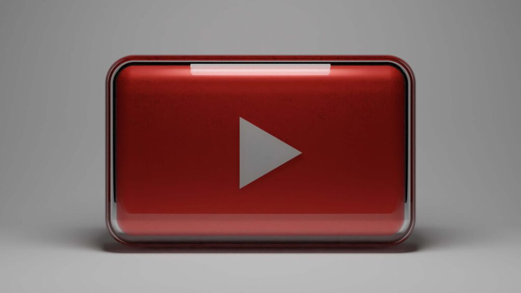 A 3D red and silver play button symbol, reminiscent of the YouTube logo, is set against a neutral gray background, evoking the fun and discovery found on the best educational YouTube channels for kids.