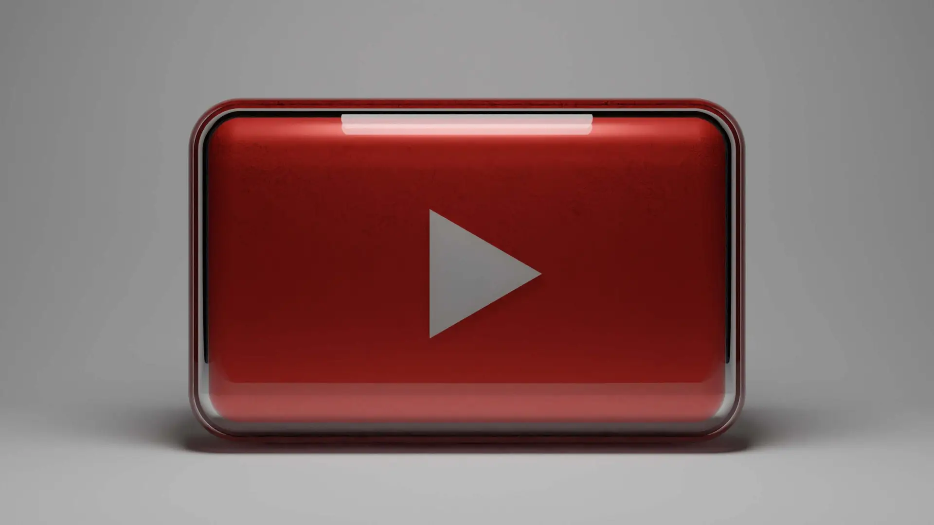 A 3D red and silver play button symbol, reminiscent of the YouTube logo, is set against a neutral gray background, evoking the fun and discovery found on the best educational YouTube channels for kids.