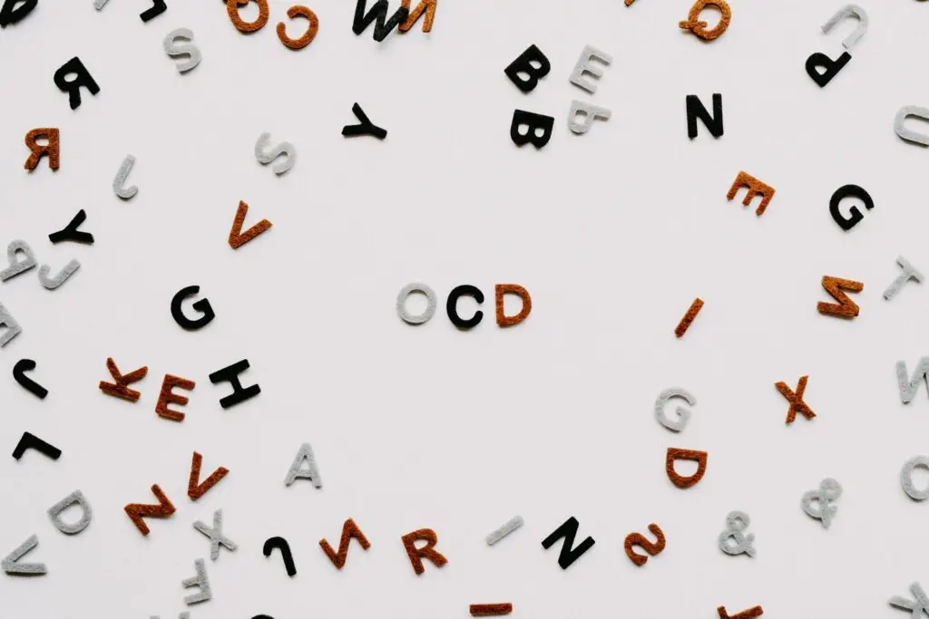 Scattered letters in various colors on a white background form the word OCD in the center, evoking thoughts about the 5 key tips on how to parent a child with OCD.