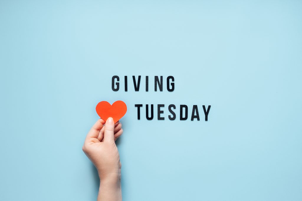 Giving Tuesday, Give, Help, Donation, Support, Volunteer concept with red heart in female hands and text Giving Tuesday on blue background. Its time to give.