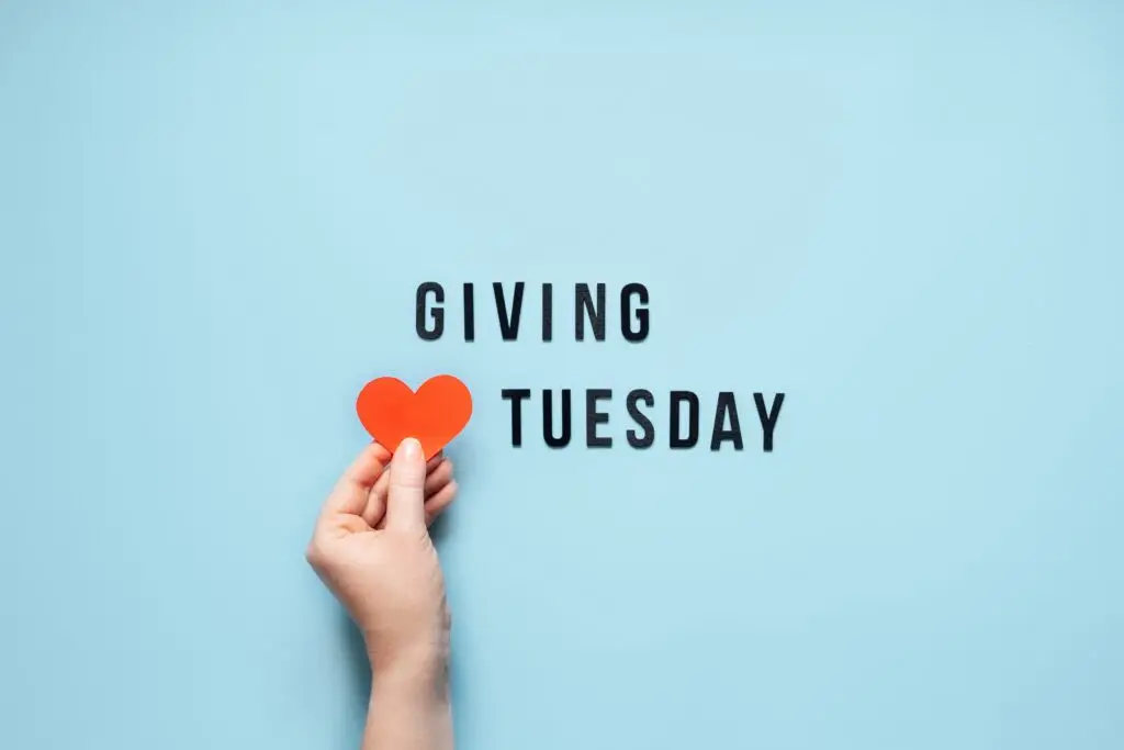 Giving Tuesday, Give, Help, Donation, Support, Volunteer concept with red heart in female hands and text Giving Tuesday on blue background. Its time to give.