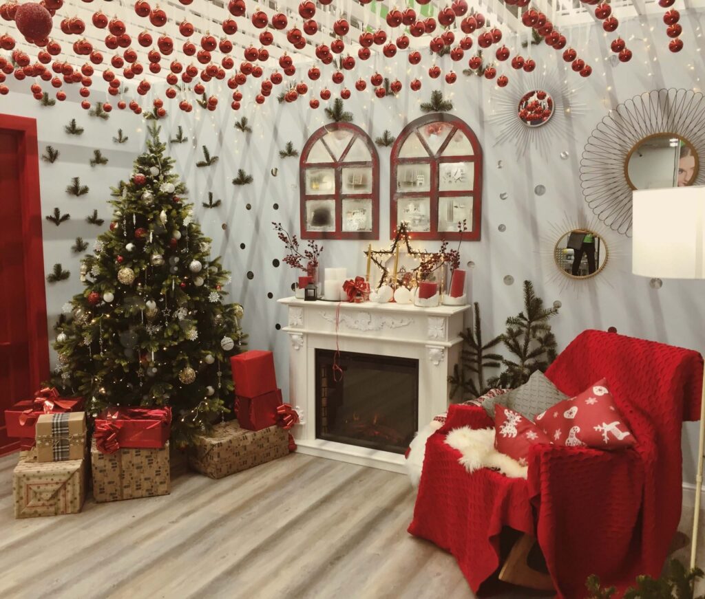 a room decorated with a christmas tree with presents and ornaments hanging from the ceiling