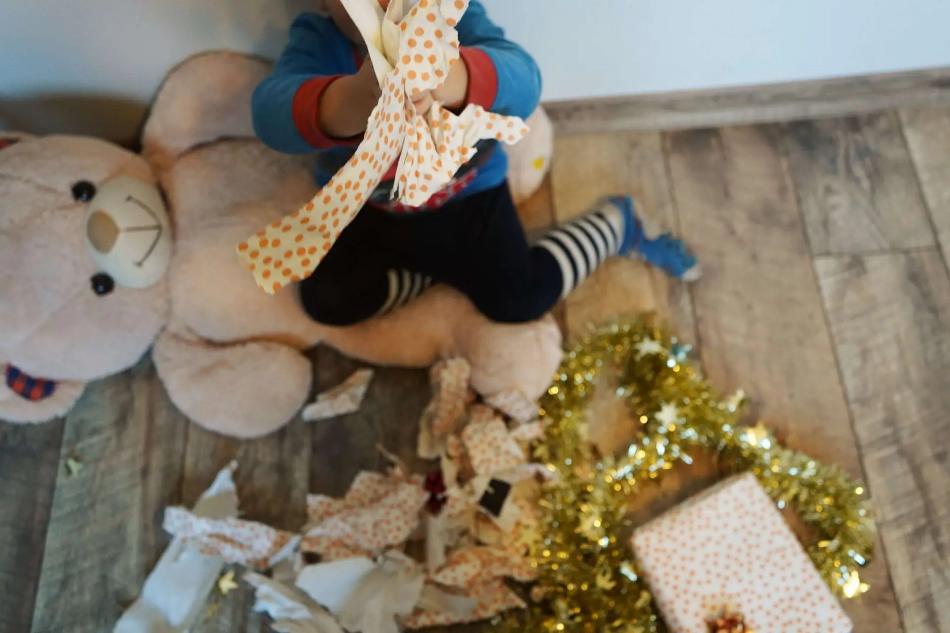 child opening up christmas presents with white and orange wrapping paper