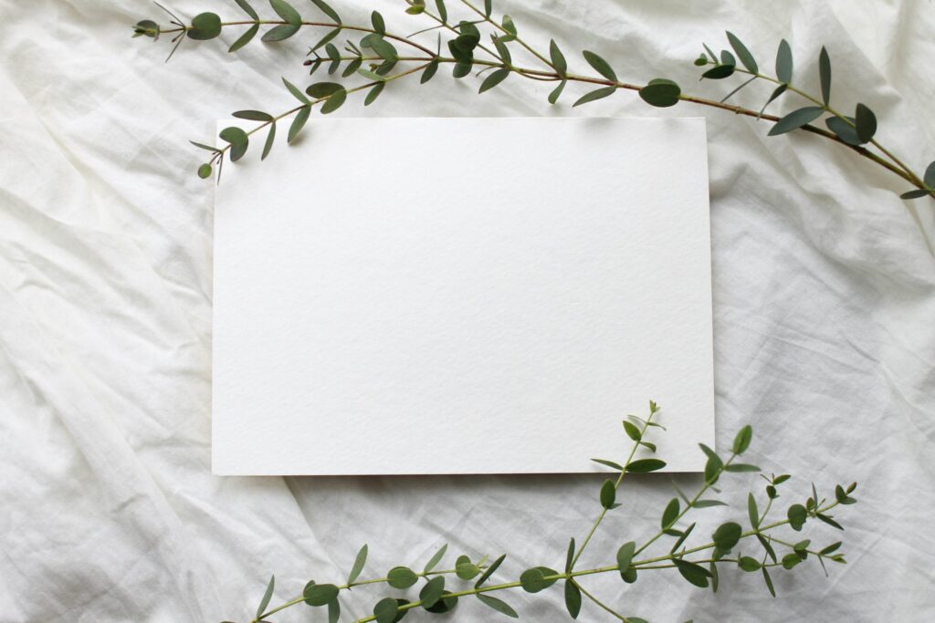 blank white piece of paper on a white sheet with greenery around it