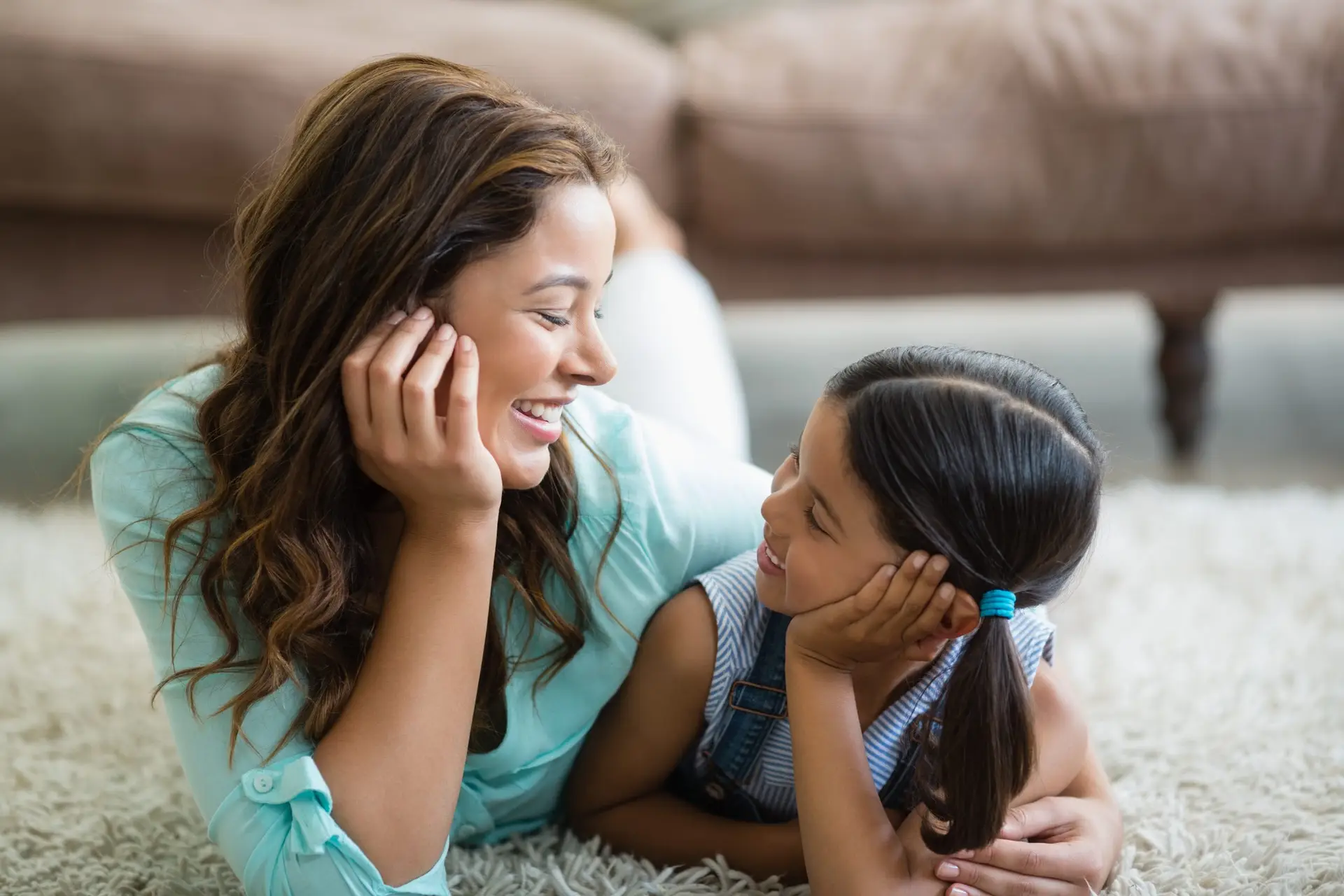 mom with her arm around her daughter cuddling on the floor