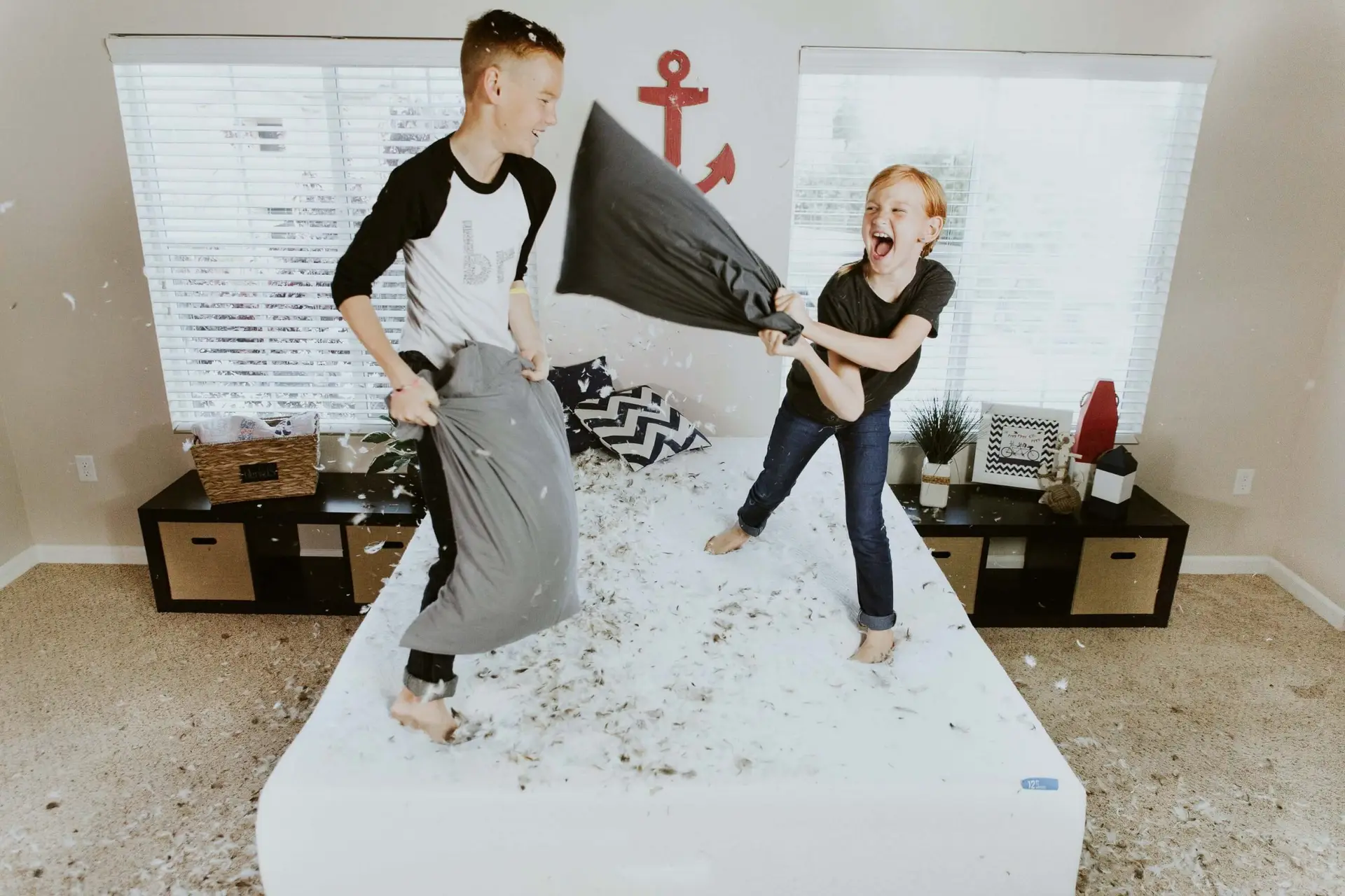 brother and sister having a pillow fight on a bed