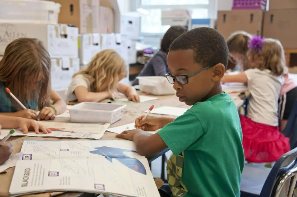 boy in green shirt drawing something in a classroom