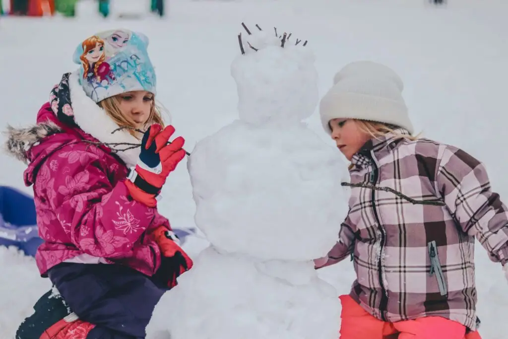 two girls building a snowman together