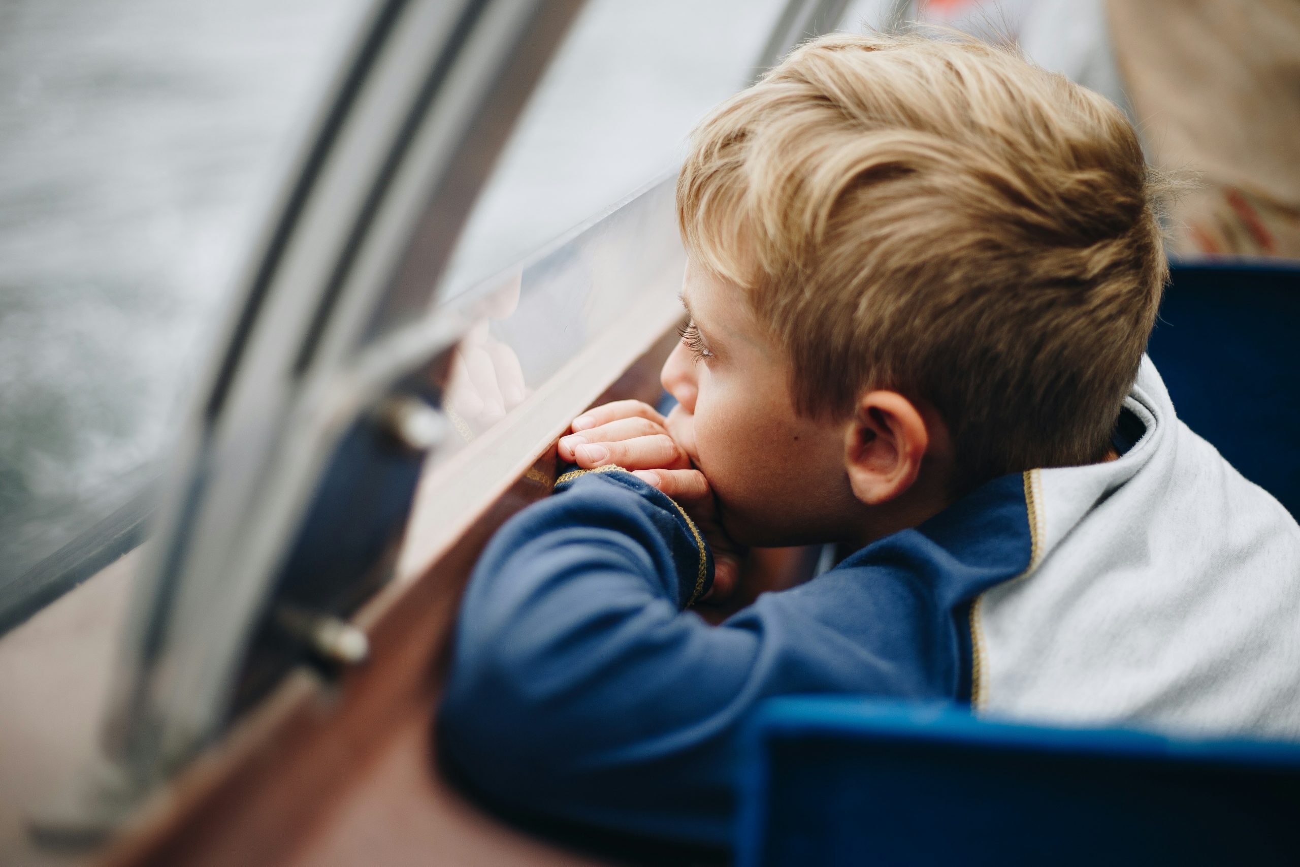 little boy looking out the window on a boat