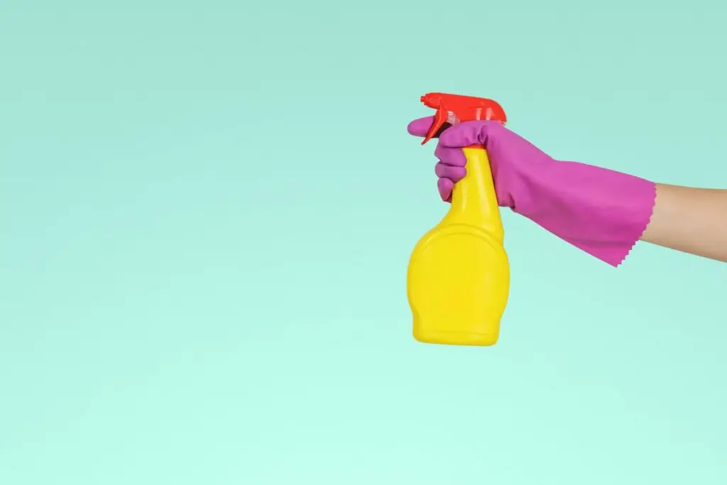 person holding yellow cleaning spray bottle