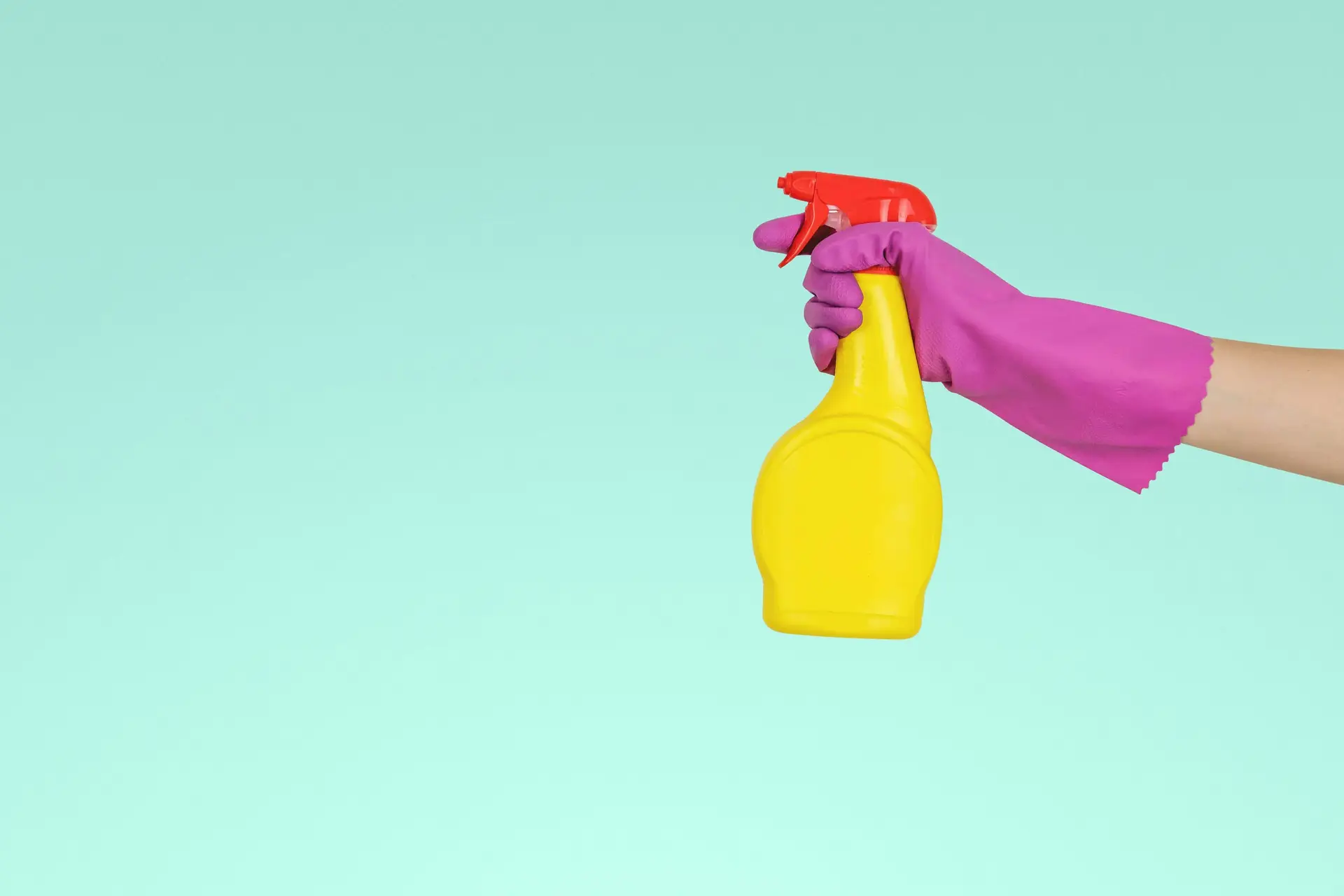 person holding yellow cleaning spray bottle