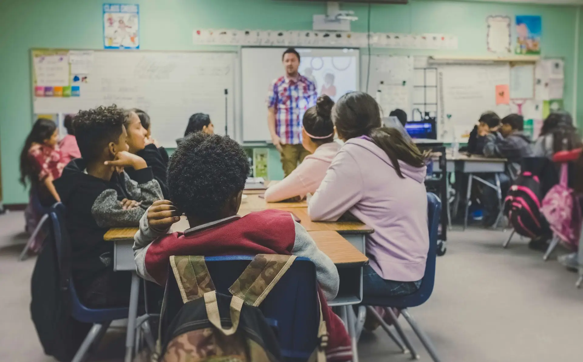 teens in a classroom listening to their teacher talk