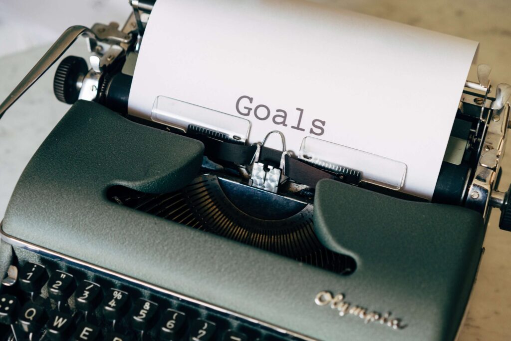 a grey typewriter with the word goals written on the paper