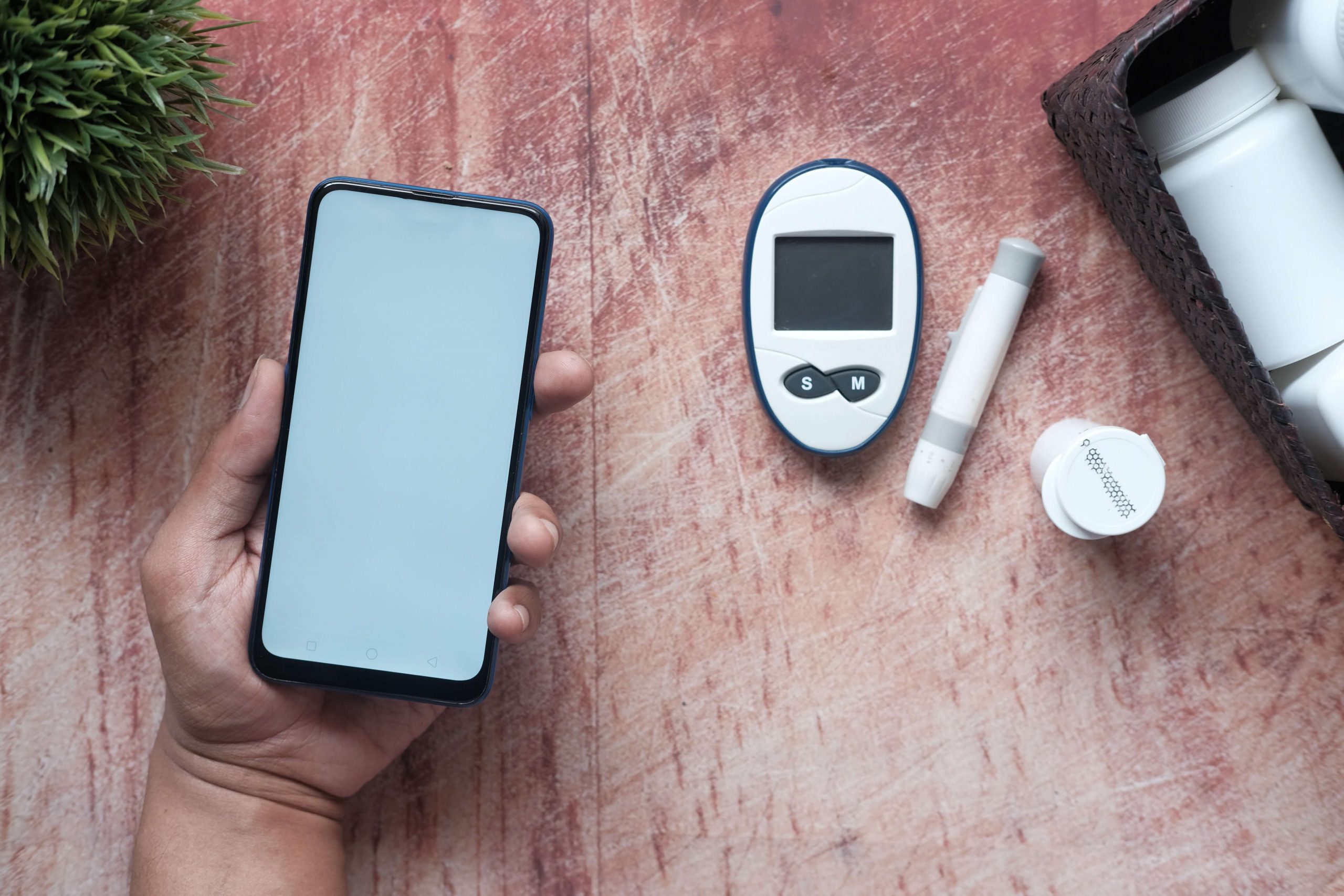 person holding a blank smartphone and diabetes devices