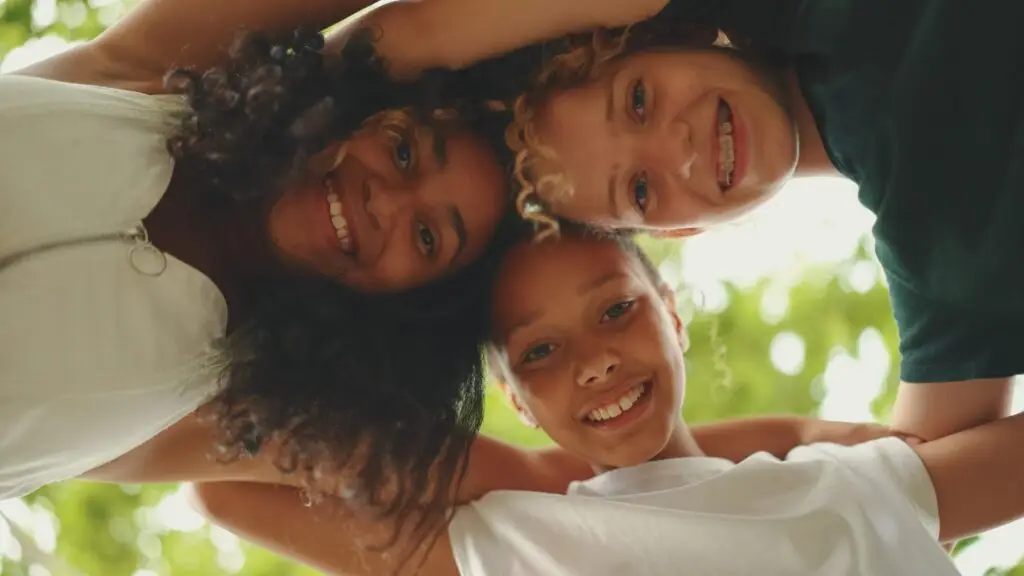 close up of the faces of three girls hugging each other standing in circle and looking directly at the camera