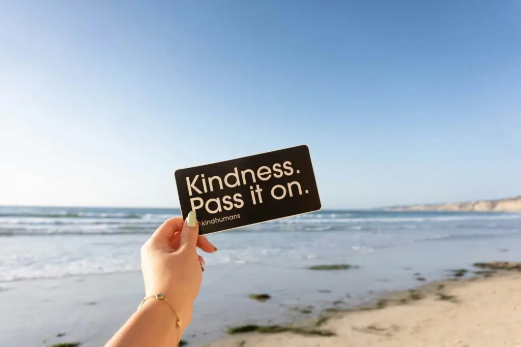 person holding kindness pass it on sticker