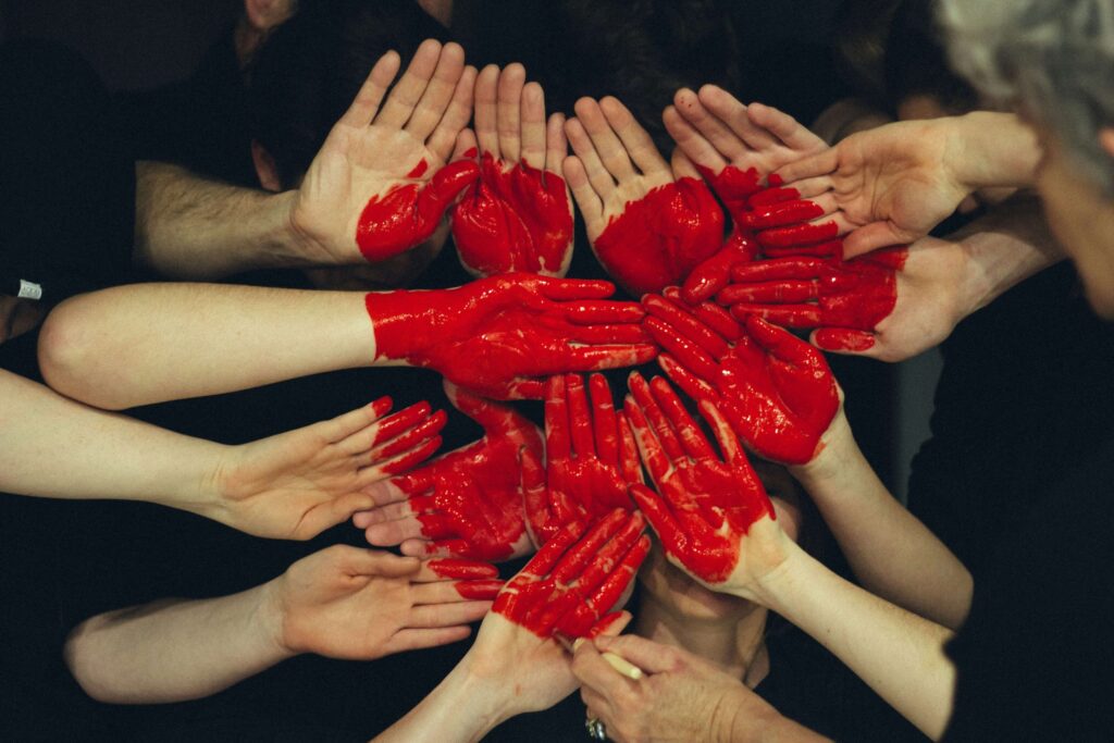 a group of hands with read paint on them