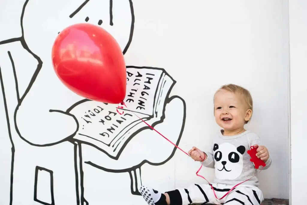 child holding red balloon