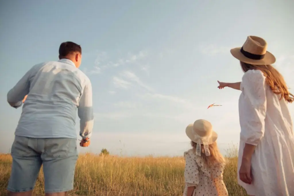 mom and dad with their daughter flying a kite