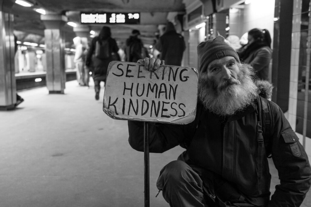 man holding a sign that says seeking human kindness