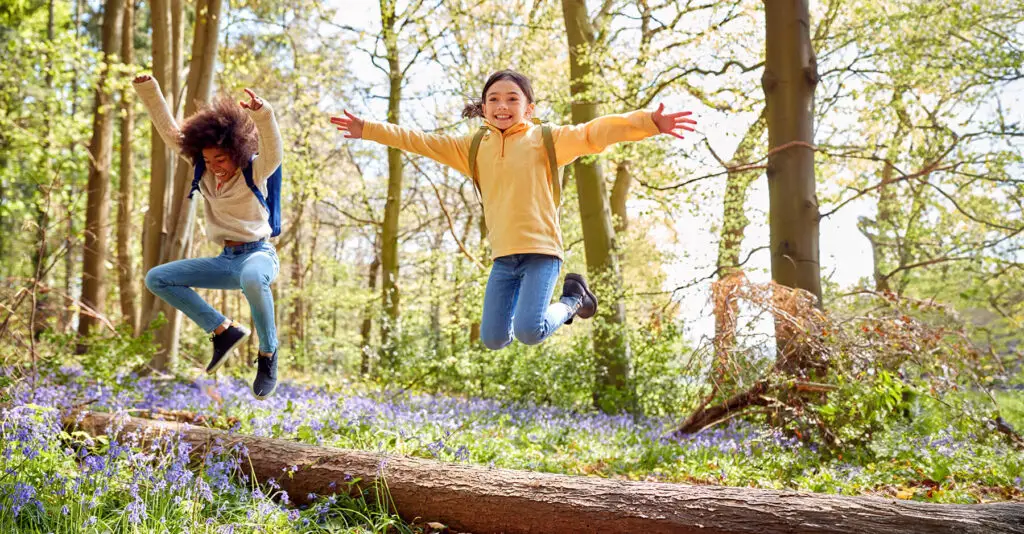 two happy kids jumping off of a log