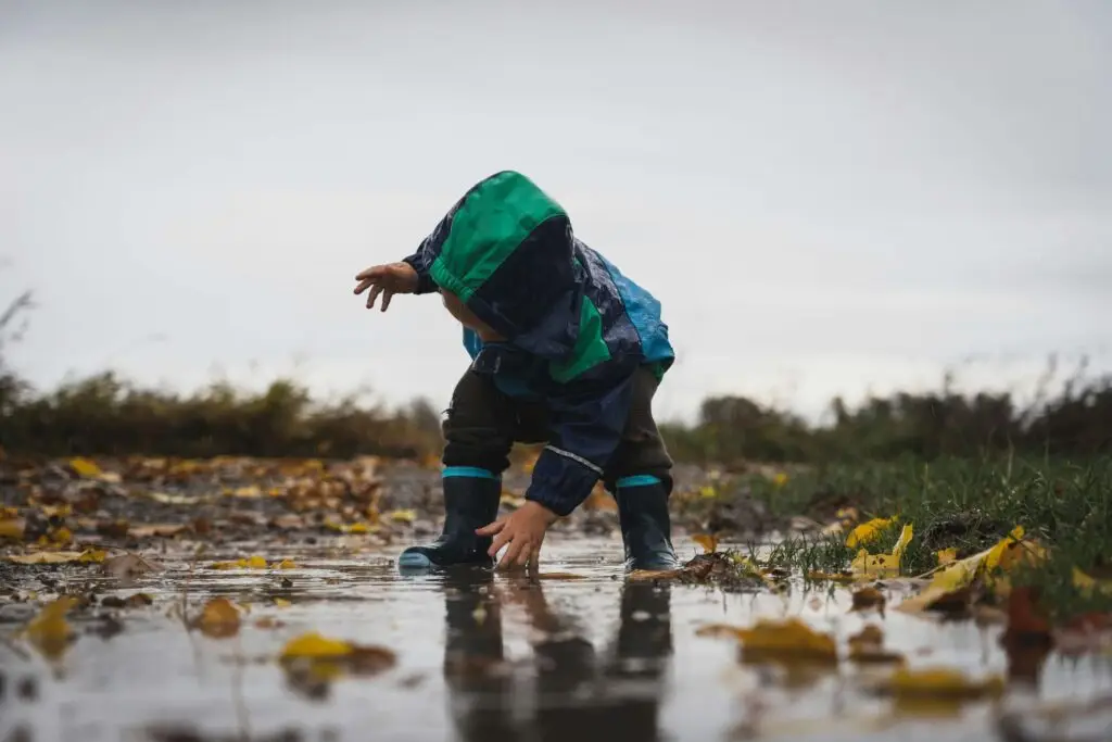 little kids playing in the rain with their rain gear on