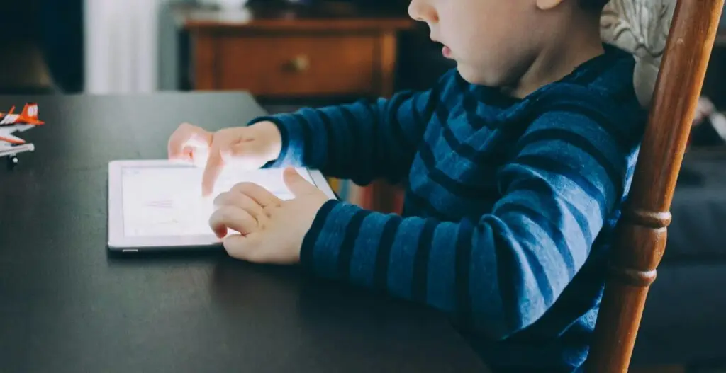 child playing on white ipad