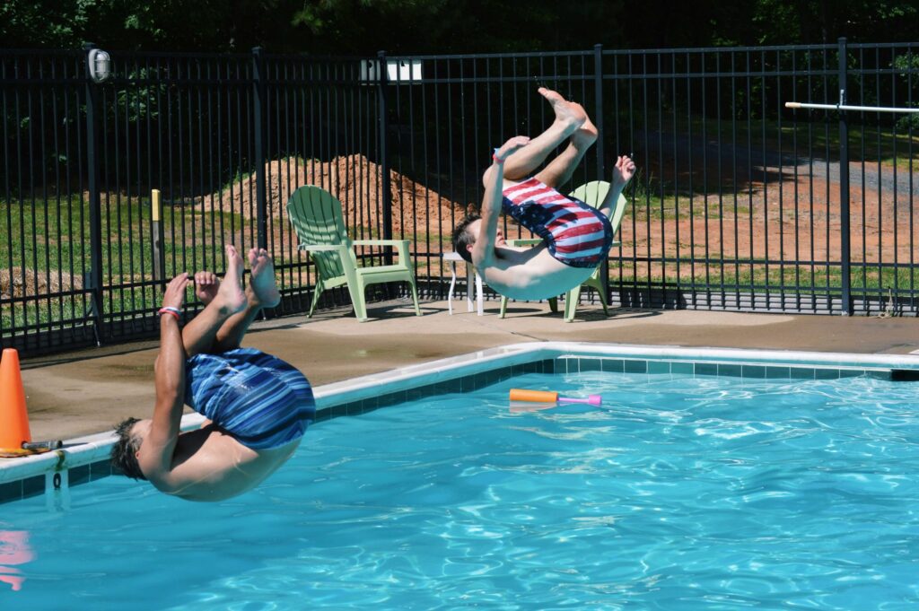 two boys jumping into a pool