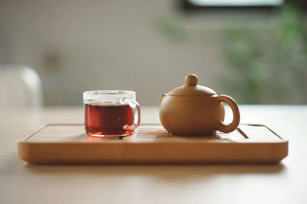 cup of tea in clear mug next to teacup