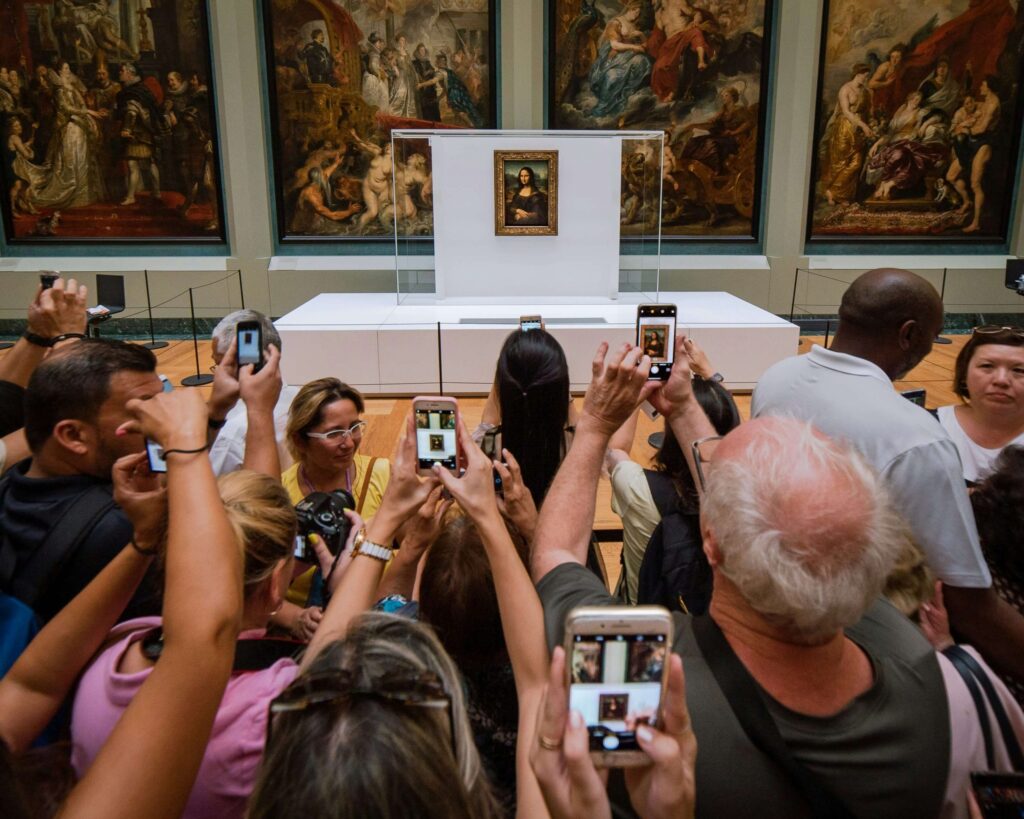 people using their smartphones to take a picture of the mona lisa