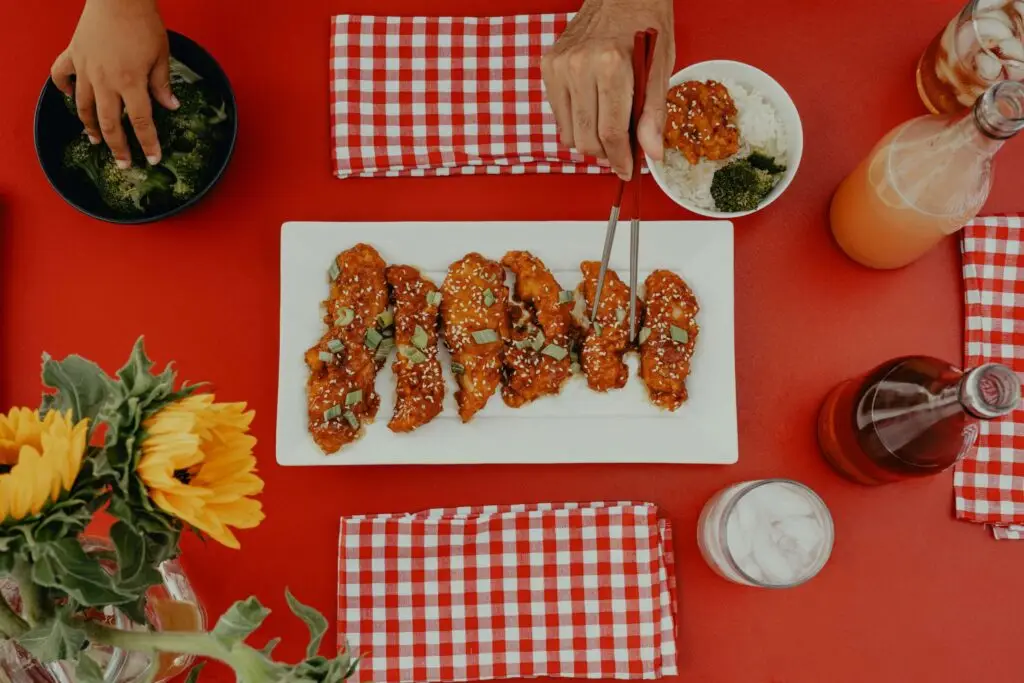 someone using chopsticks to grab a piece of chicken on plate