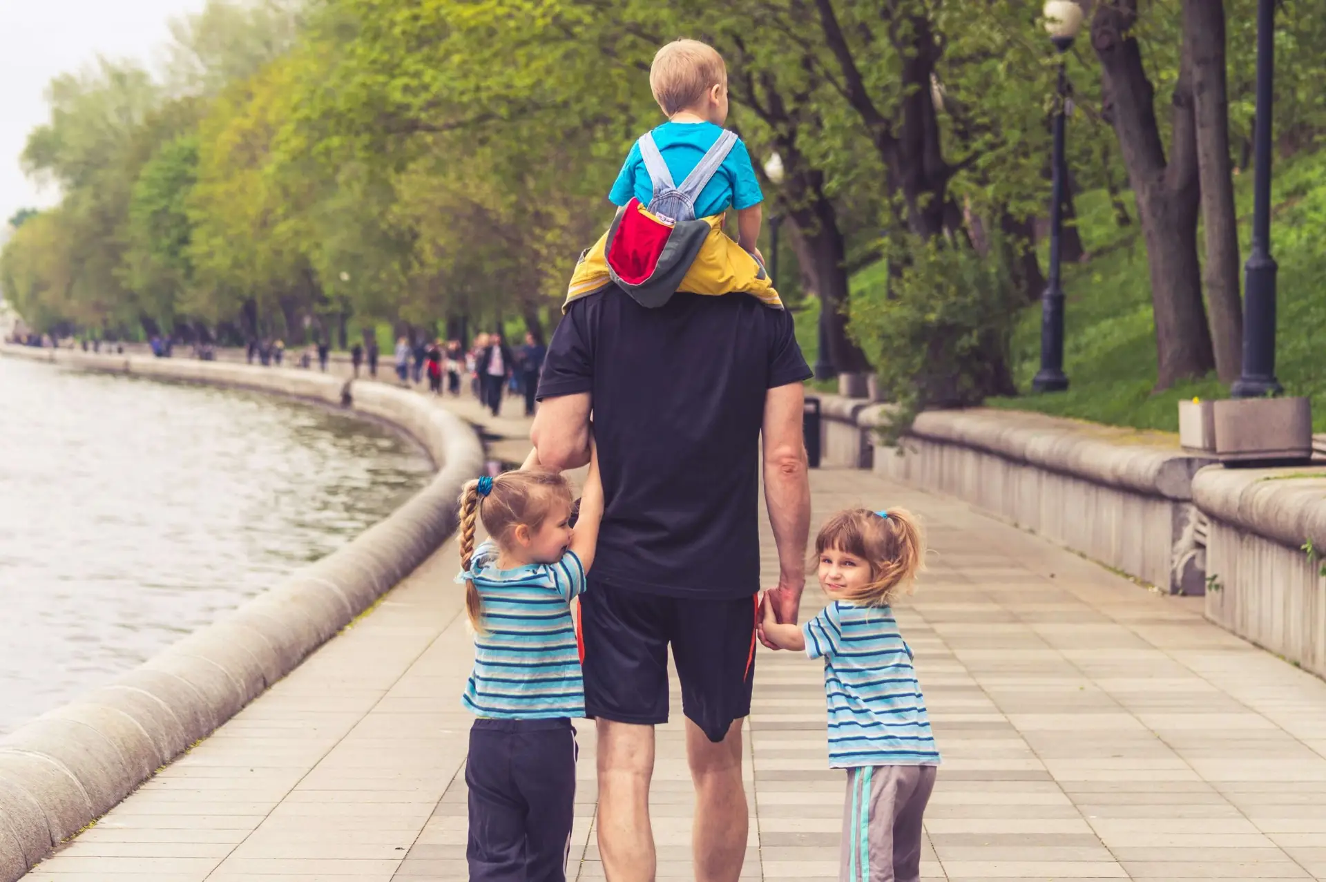 three kids walking through the park with their dad