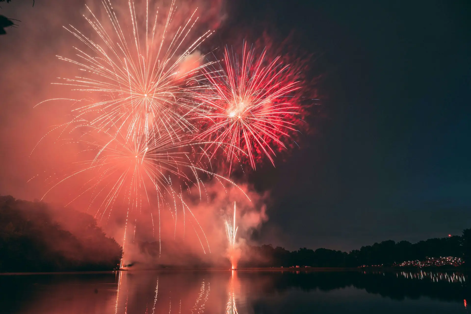 fireworks going off over lake at night