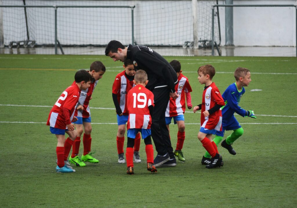 kids huddling with coach for soccer game