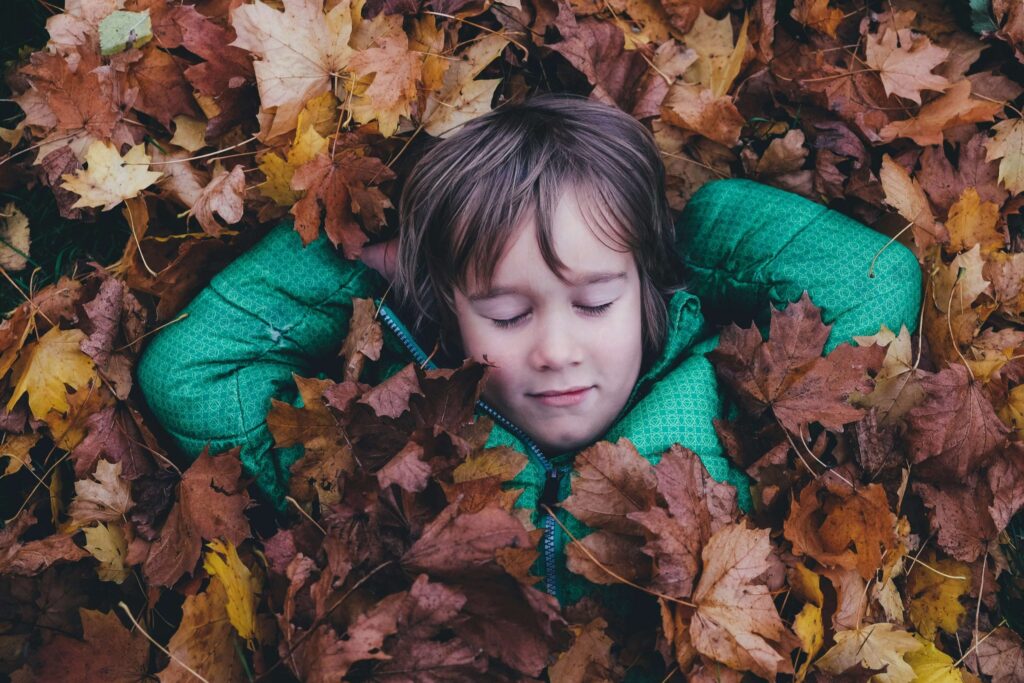 kid laying in a pile of leaves