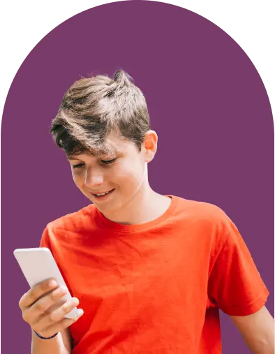 A young person in a red shirt is smiling while looking at a smartphone. The background is a solid purple color.