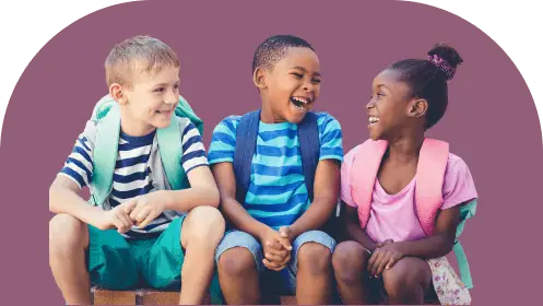 Three smiling children sit together in front of a purple background. They are wearing backpacks and casual summer clothes. All are looking at each other joyfully, sharing a moment of laughter.