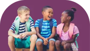 Three children sitting and laughing together against a purple background. The kids, dressed in casual summer clothes with backpacks, appear joyful and friendly.