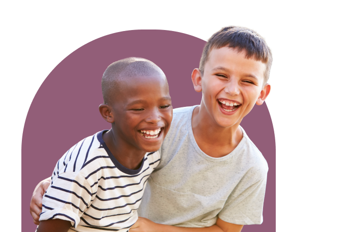 Two boys laughing joyfully, one wearing a striped shirt and the other in a gray t-shirt, with a maroon semi-circular background. They appear to be having fun together.